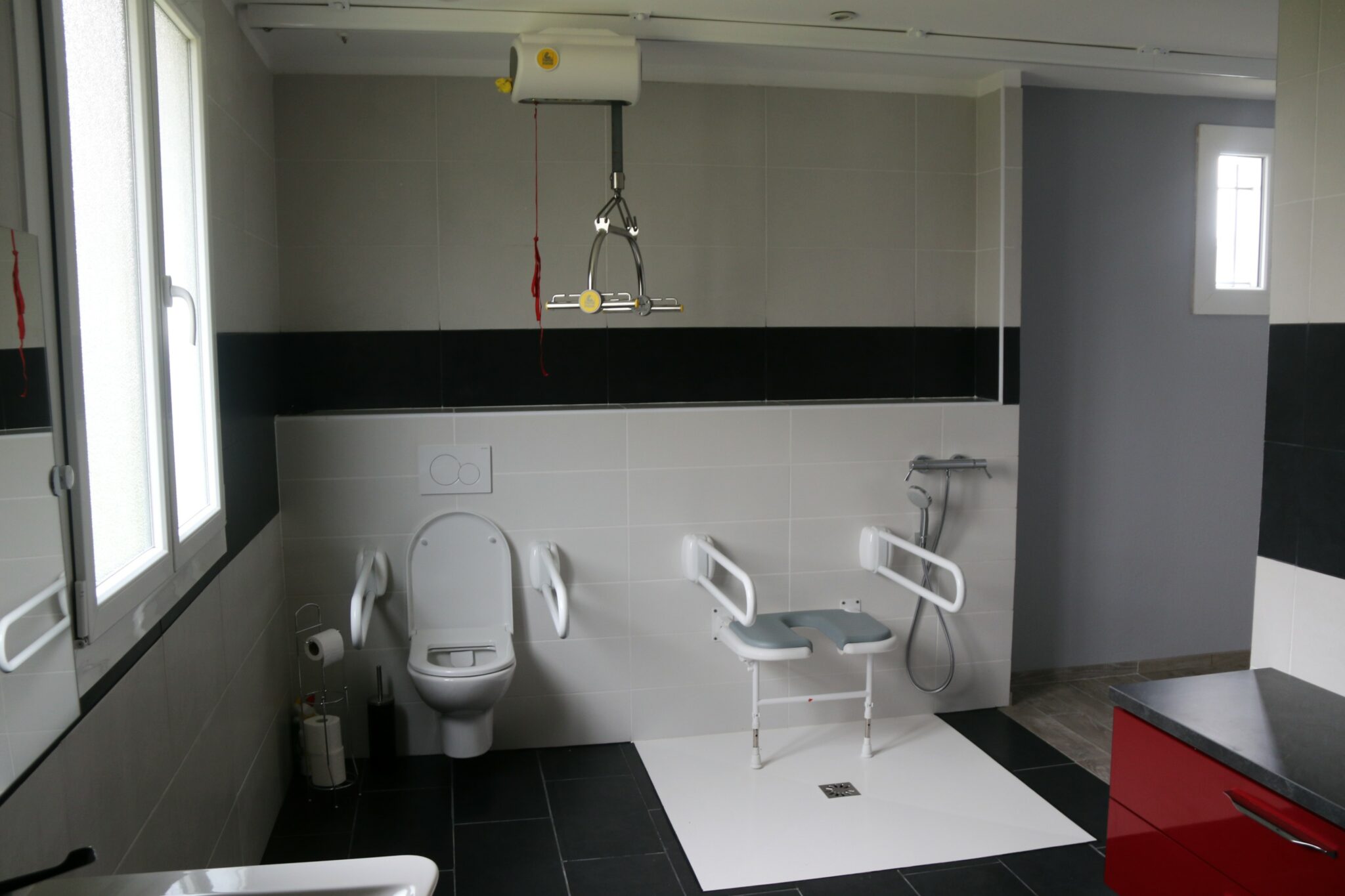 Salle de bain accessible avec rail de transfert au plafond et douche à l'italienne