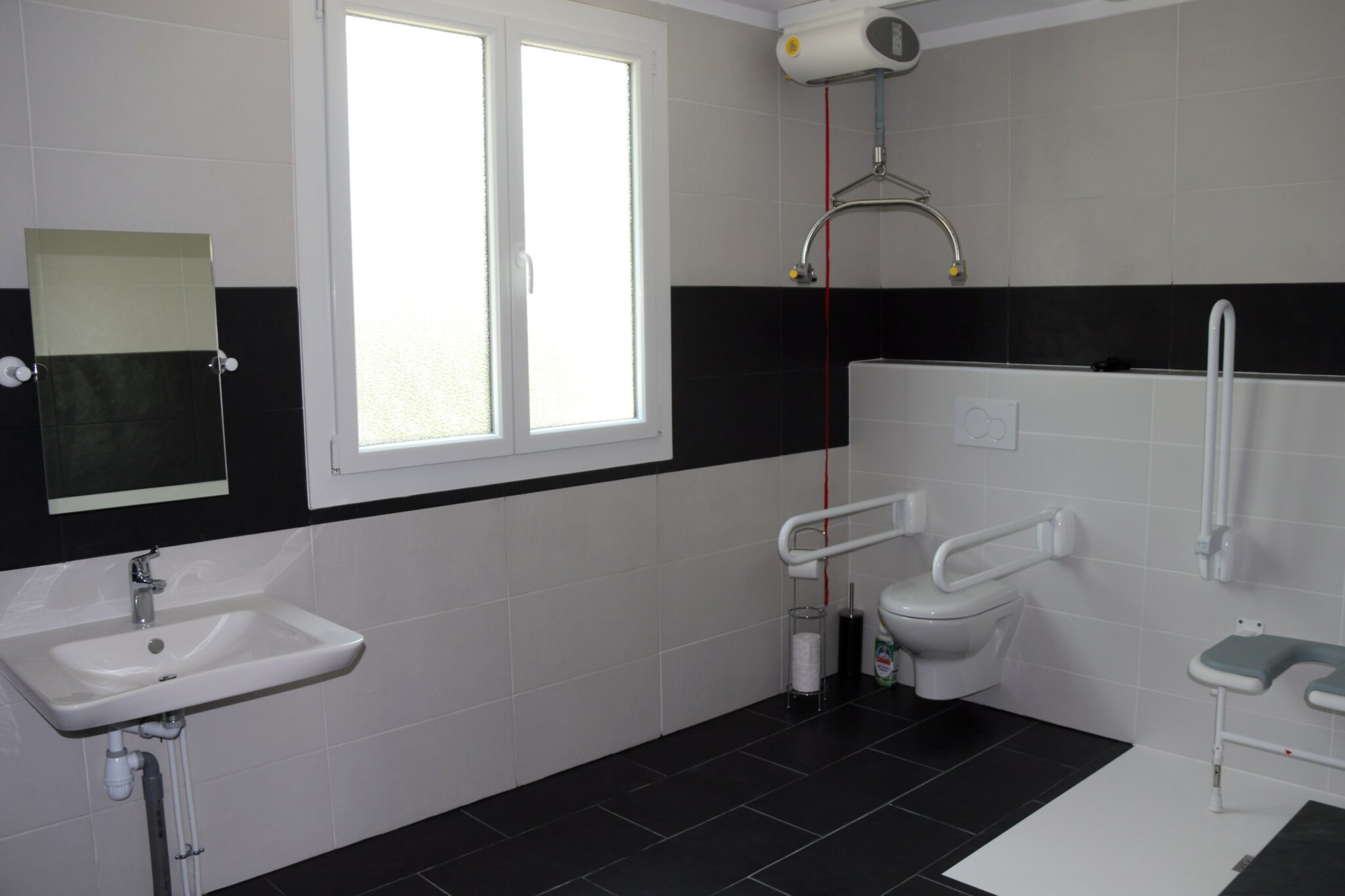 Salle de bain accessible avec rail de transfert au plafond et douche à l'italienne